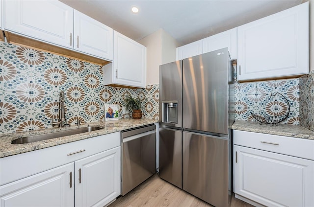 kitchen with stainless steel appliances, tasteful backsplash, a sink, and white cabinetry