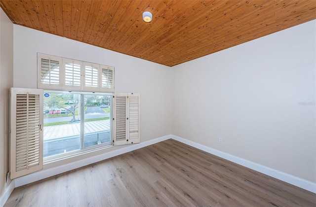 spare room featuring wood ceiling, baseboards, and wood finished floors