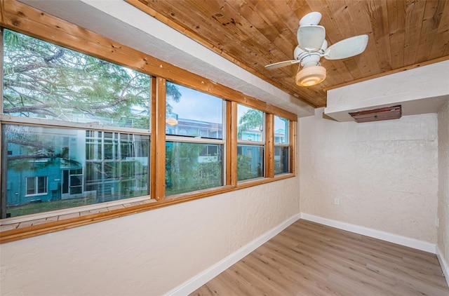 unfurnished room featuring ceiling fan, a textured wall, wooden ceiling, wood finished floors, and baseboards