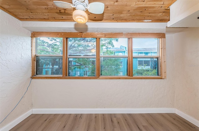 spare room featuring wooden ceiling, a healthy amount of sunlight, light wood-style flooring, and baseboards