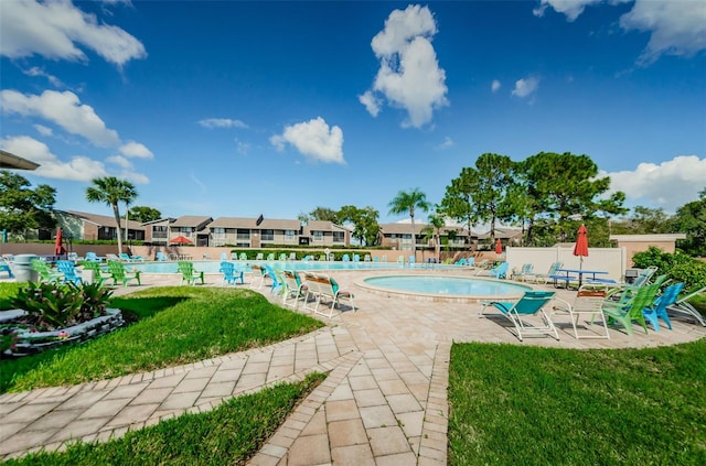 pool with a patio area, fence, and a lawn