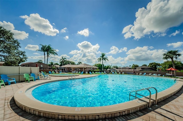 community pool with a patio area and fence