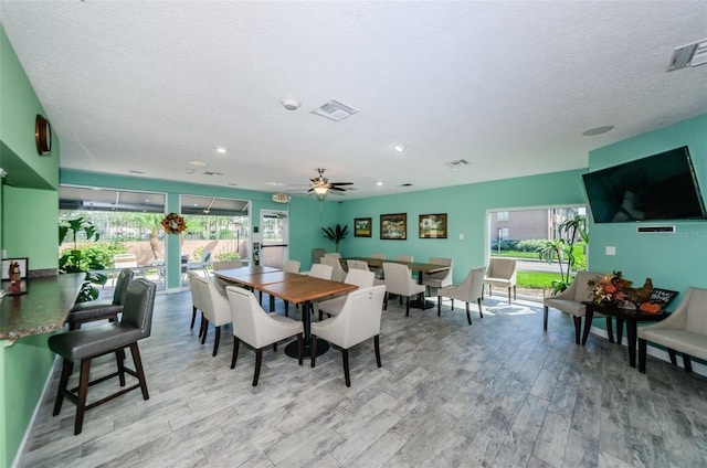 dining area featuring a textured ceiling, light wood finished floors, and visible vents