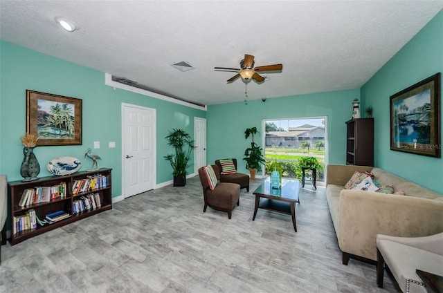 living room featuring visible vents, ceiling fan, a textured ceiling, and baseboards