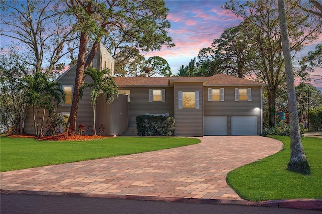 view of front of house featuring a garage, decorative driveway, and a lawn