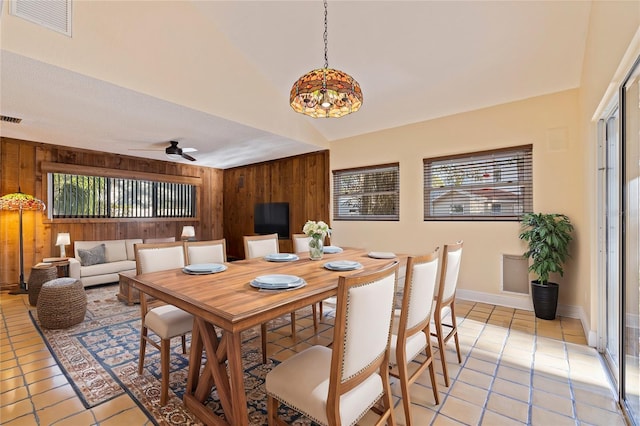 dining area with lofted ceiling, light tile patterned floors, wood walls, and visible vents