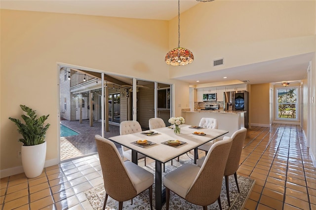 tiled dining room with a towering ceiling, visible vents, and baseboards