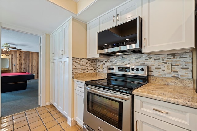 kitchen featuring light tile patterned floors, white cabinets, light stone countertops, stainless steel appliances, and backsplash