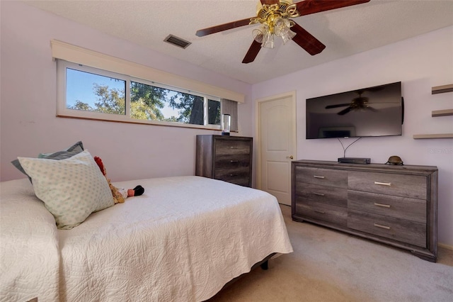 bedroom with light carpet, ceiling fan, visible vents, and a textured ceiling