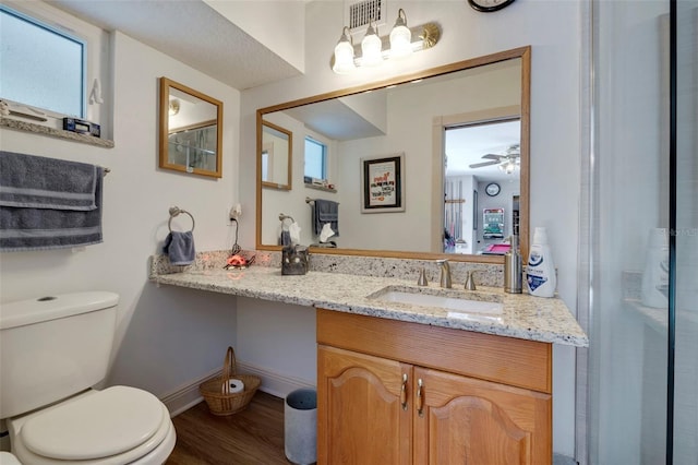 bathroom with visible vents, baseboards, toilet, wood finished floors, and vanity