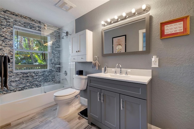 full bathroom featuring a textured wall, shower / bath combination with glass door, wood finished floors, and vanity