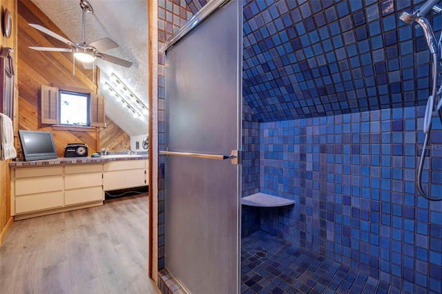 bathroom featuring wood finished floors, vaulted ceiling, a textured ceiling, vanity, and wood walls