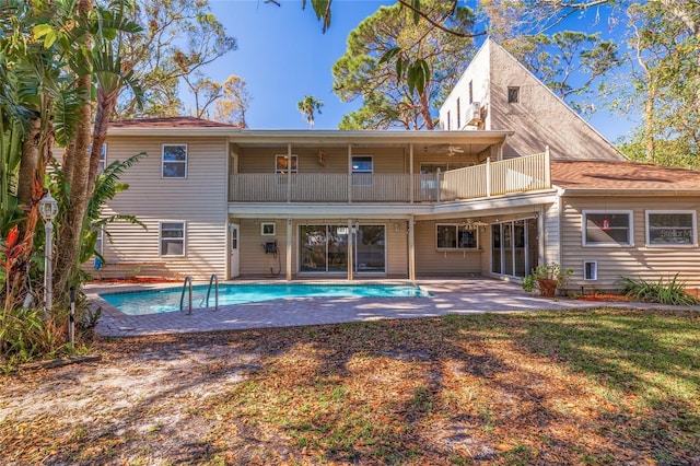 back of house with a balcony, an outdoor pool, and a patio