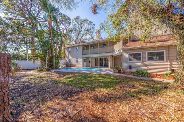 rear view of property with a fenced in pool, a patio area, fence, and a balcony