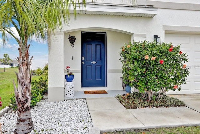 property entrance featuring a garage and stucco siding