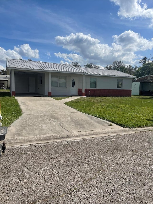 single story home with metal roof, brick siding, driveway, a carport, and a front yard