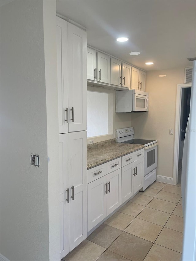 kitchen with white appliances, baseboards, light tile patterned floors, and white cabinetry