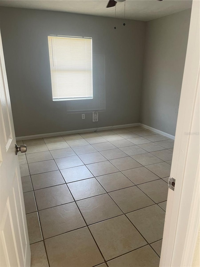 unfurnished room featuring ceiling fan, baseboards, and light tile patterned floors