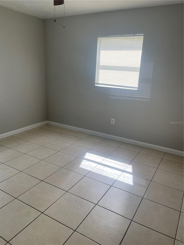 spare room featuring light tile patterned floors and baseboards