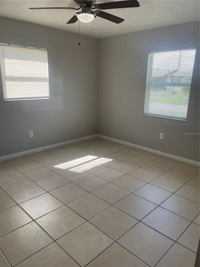 unfurnished room with ceiling fan, baseboards, and light tile patterned floors