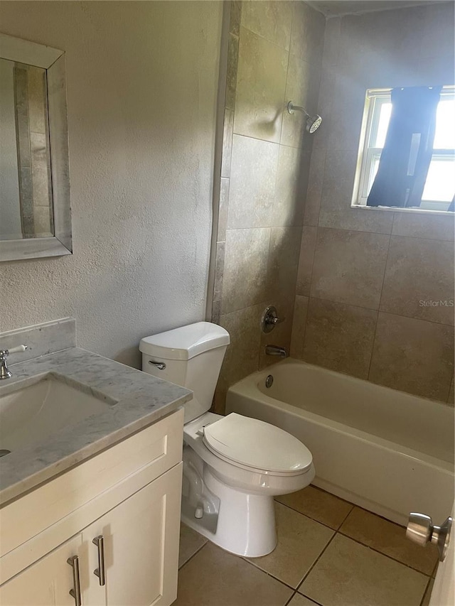 bathroom with a textured wall, toilet, vanity, shower / washtub combination, and tile patterned floors