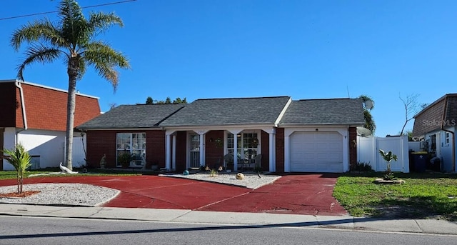 ranch-style home featuring a garage, fence, concrete driveway, and roof with shingles