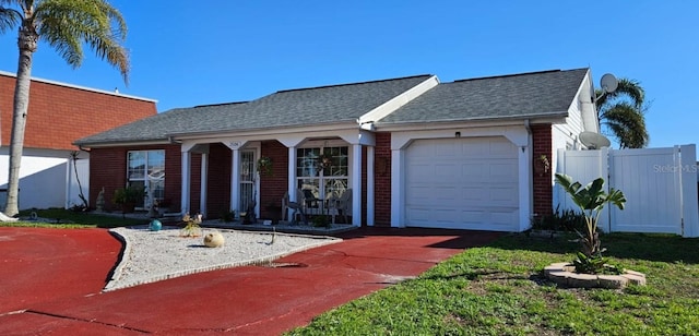 ranch-style house featuring a garage, brick siding, roof with shingles, and fence