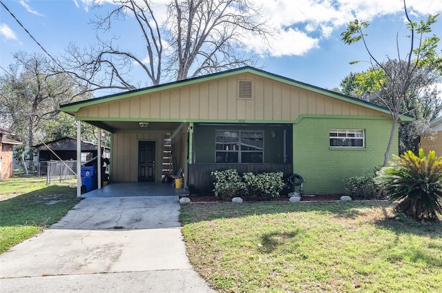 view of front of property featuring a carport, a front yard, concrete driveway, and brick siding