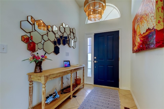 foyer entrance featuring tile patterned floors, baseboards, and a chandelier