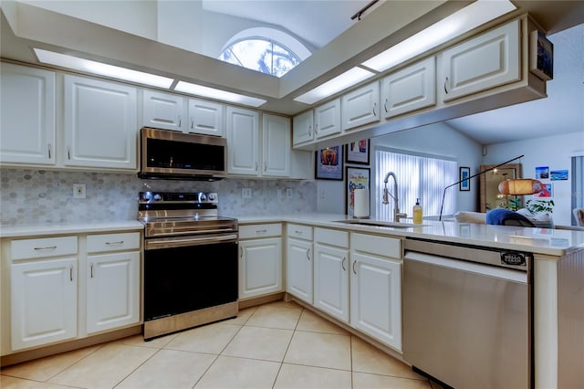 kitchen with light tile patterned floors, a peninsula, a sink, stainless steel appliances, and light countertops