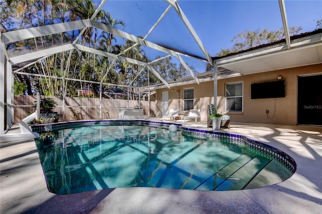 view of swimming pool featuring glass enclosure, a patio, fence, and a fenced in pool