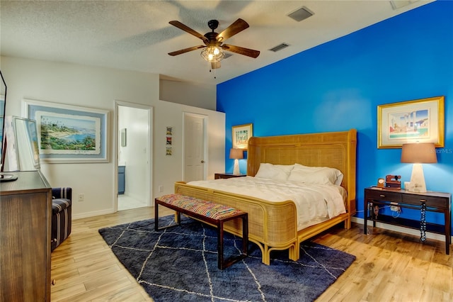 bedroom with visible vents, a textured ceiling, light wood-style flooring, and vaulted ceiling