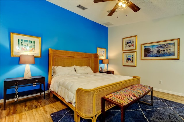 bedroom featuring visible vents, a ceiling fan, baseboards, and wood finished floors