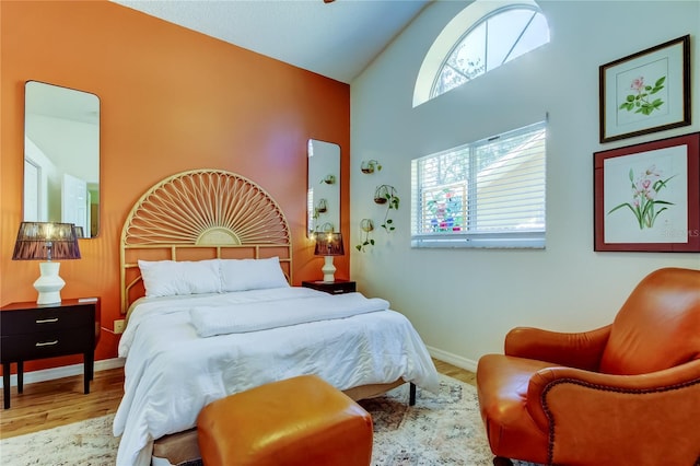 bedroom with baseboards, high vaulted ceiling, and wood finished floors