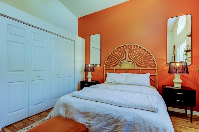 bedroom with wood finished floors, a closet, and baseboards