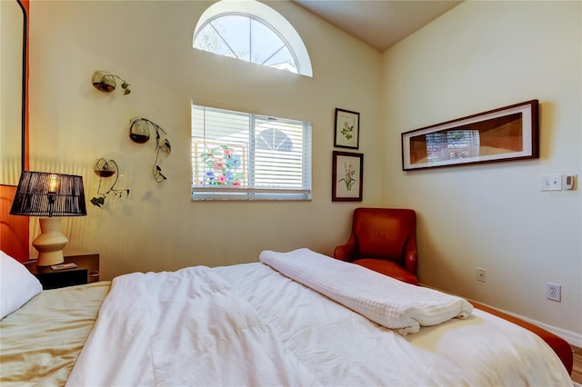 bedroom with baseboards, multiple windows, and lofted ceiling