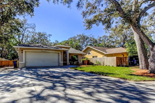 ranch-style home featuring a garage, stucco siding, driveway, and fence