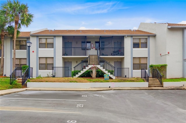 view of property with uncovered parking and stairway