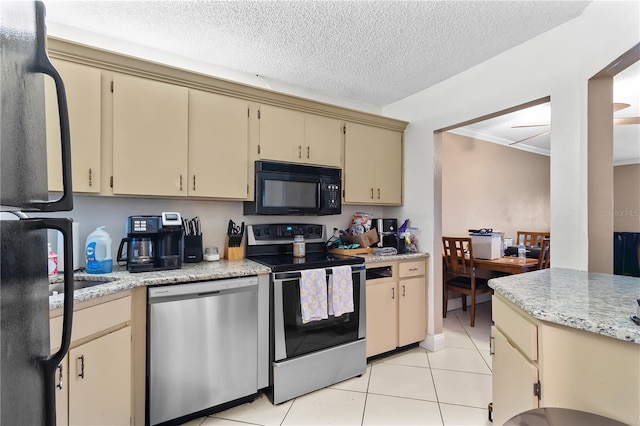 kitchen with black appliances, light tile patterned floors, cream cabinetry, and a textured ceiling