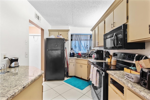 kitchen featuring a textured ceiling, cream cabinets, visible vents, light countertops, and black appliances