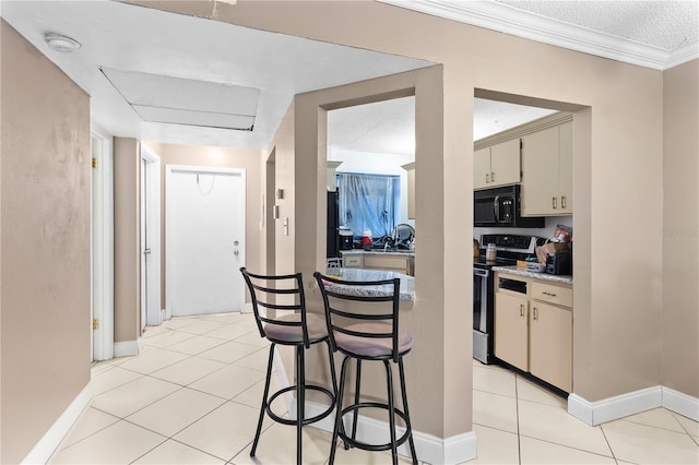 kitchen featuring black microwave, stainless steel range with electric cooktop, cream cabinets, and light tile patterned flooring