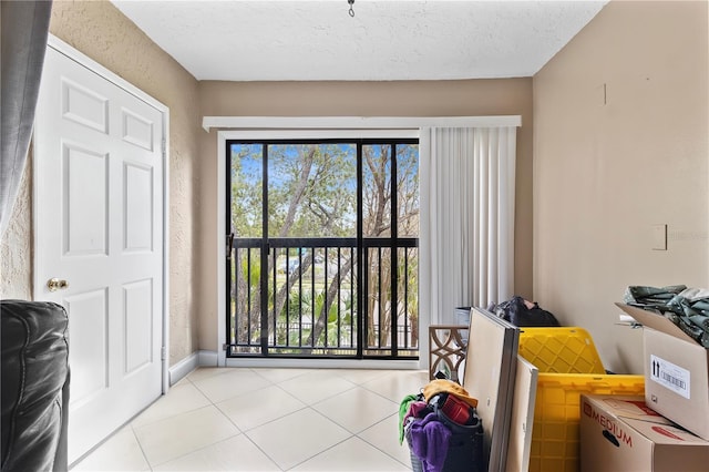 doorway to outside featuring a textured ceiling, a textured wall, plenty of natural light, and tile patterned flooring