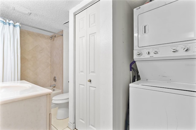 laundry area featuring light tile patterned floors, visible vents, a sink, a textured ceiling, and stacked washing maching and dryer