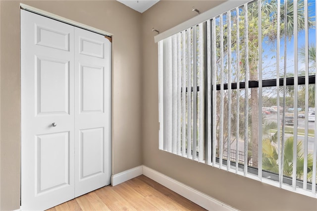 unfurnished bedroom featuring multiple windows, wood finished floors, and baseboards