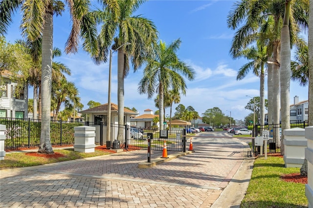 view of street featuring a residential view, a gated entry, curbs, a gate, and street lights