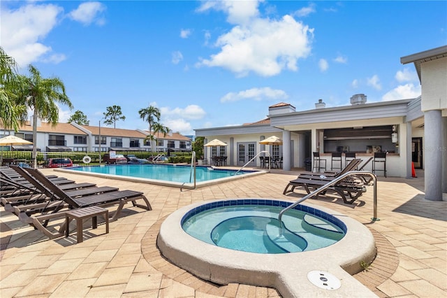 pool with fence, a community hot tub, french doors, and a patio