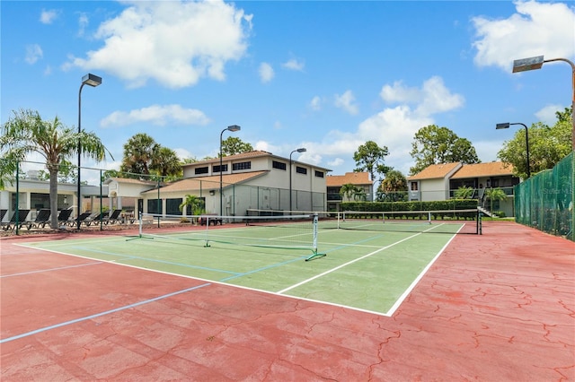 view of tennis court with community basketball court and fence