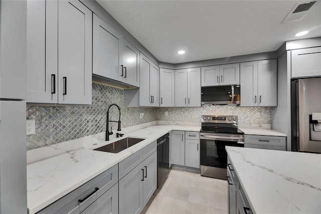 kitchen featuring appliances with stainless steel finishes, gray cabinets, a sink, and visible vents