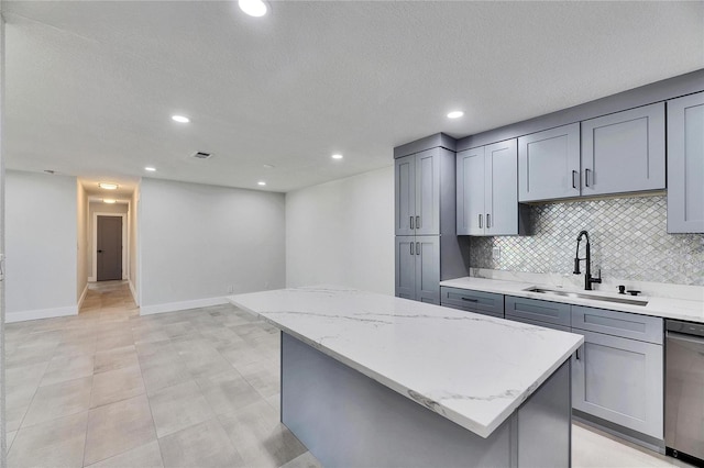 kitchen featuring a kitchen island, a sink, gray cabinets, decorative backsplash, and dishwasher