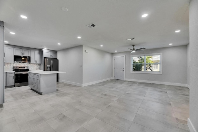 kitchen featuring visible vents, decorative backsplash, a kitchen island, open floor plan, and stainless steel appliances